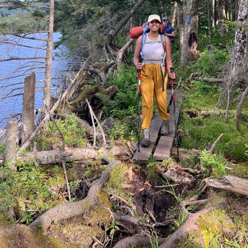 Backpacker crossing a bog bridge