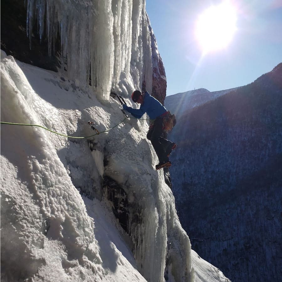 A climber scales an icy cliff