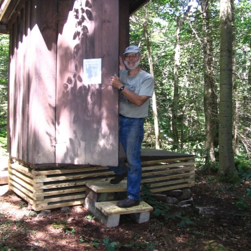 Man standing at a privy door