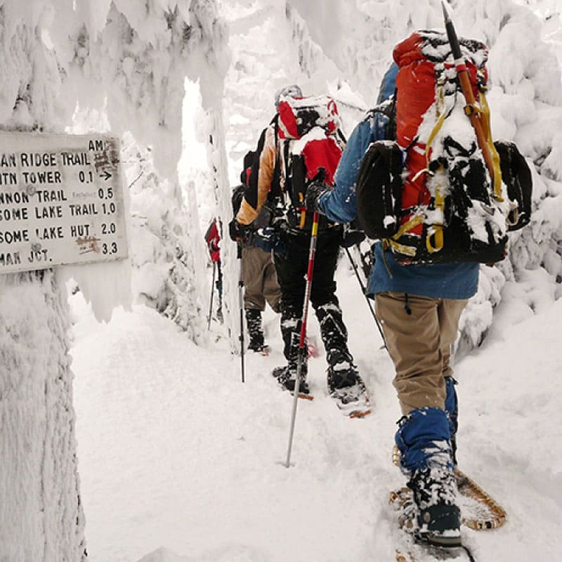 A group snowshoes on a hiking trail