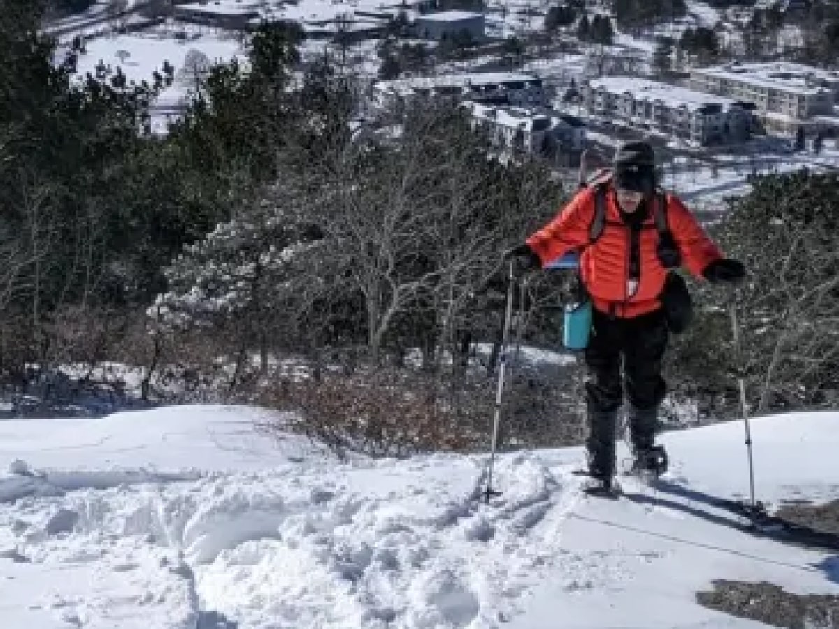 Front cover: Man snowshoeing on a hill overlooking a city