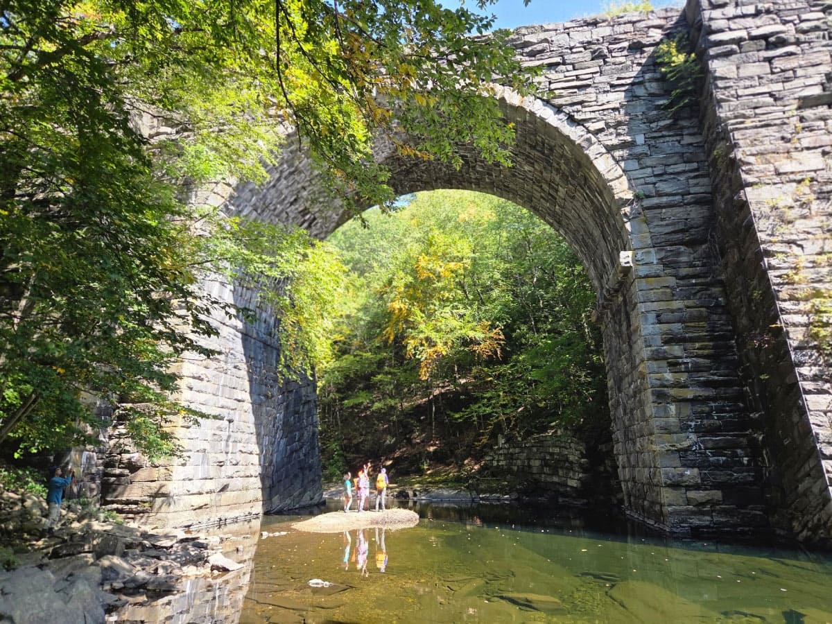 Hikers below a stone bridge