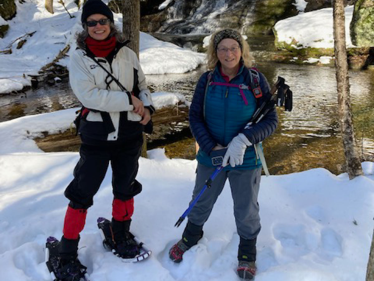 Two snowshoers in front of a waterfall 