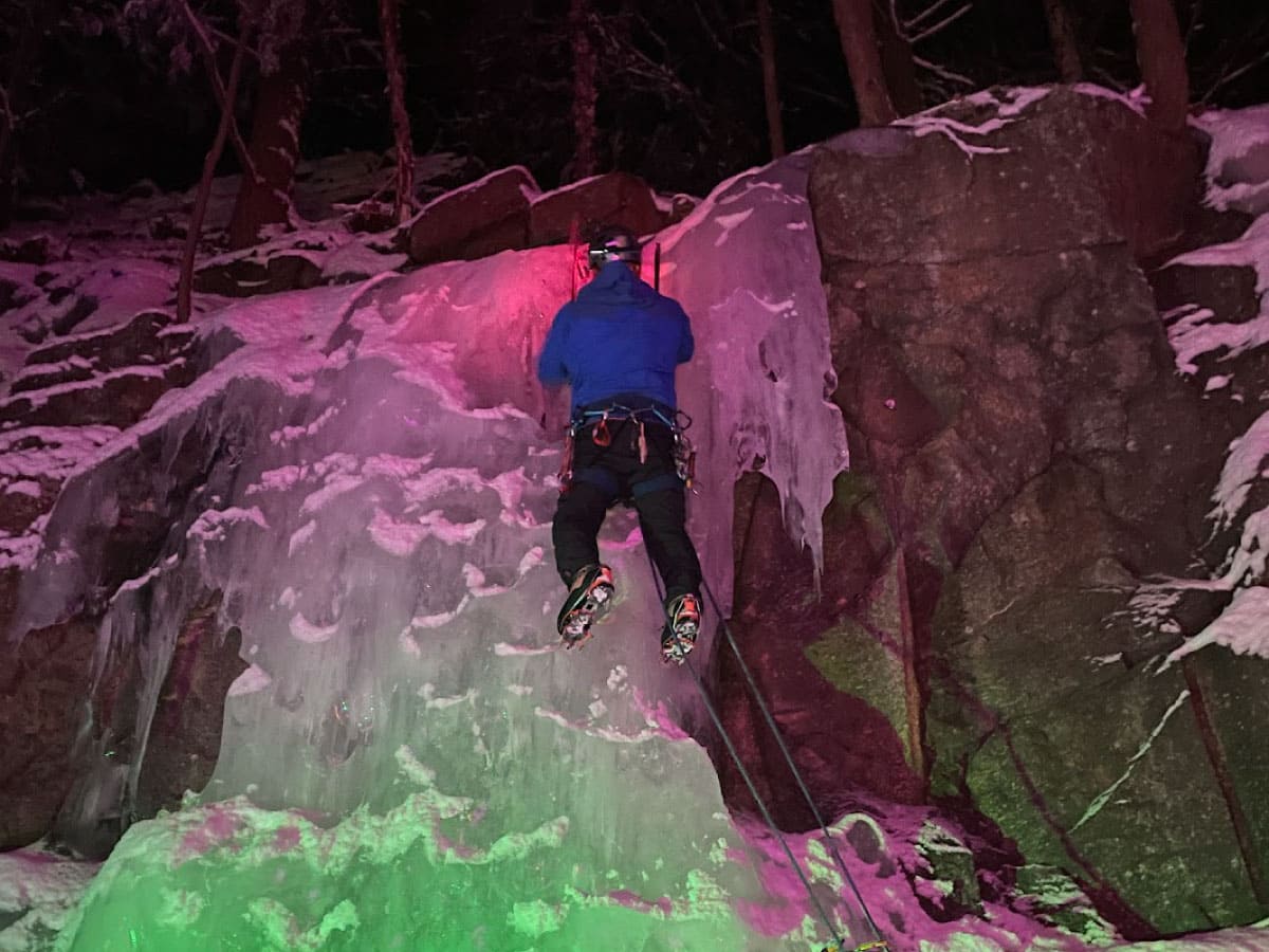 A climber scales an icy cliff