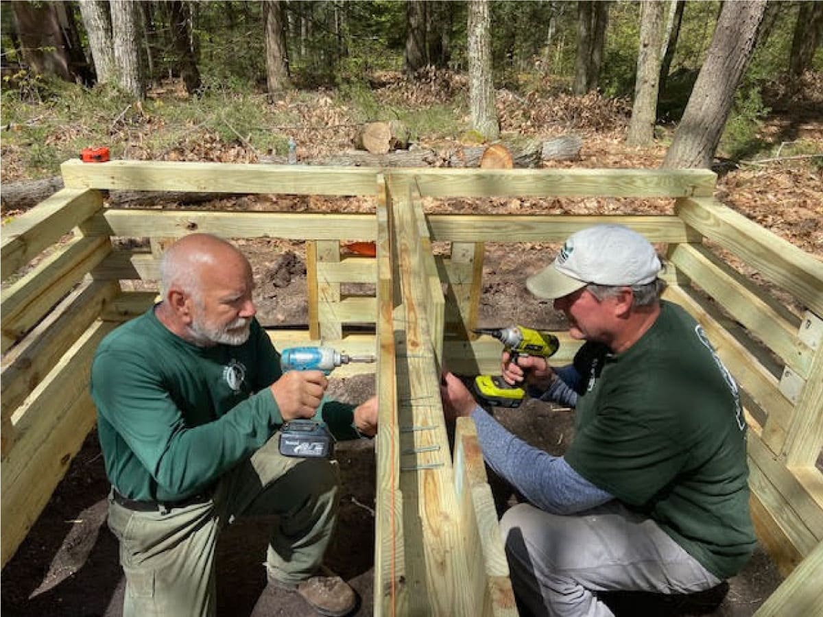 Workers construct the cribbed foundation of the privy