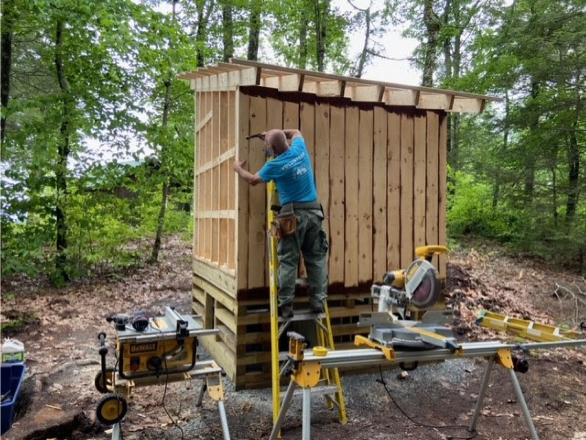 A worker constructs the walls of the new privy