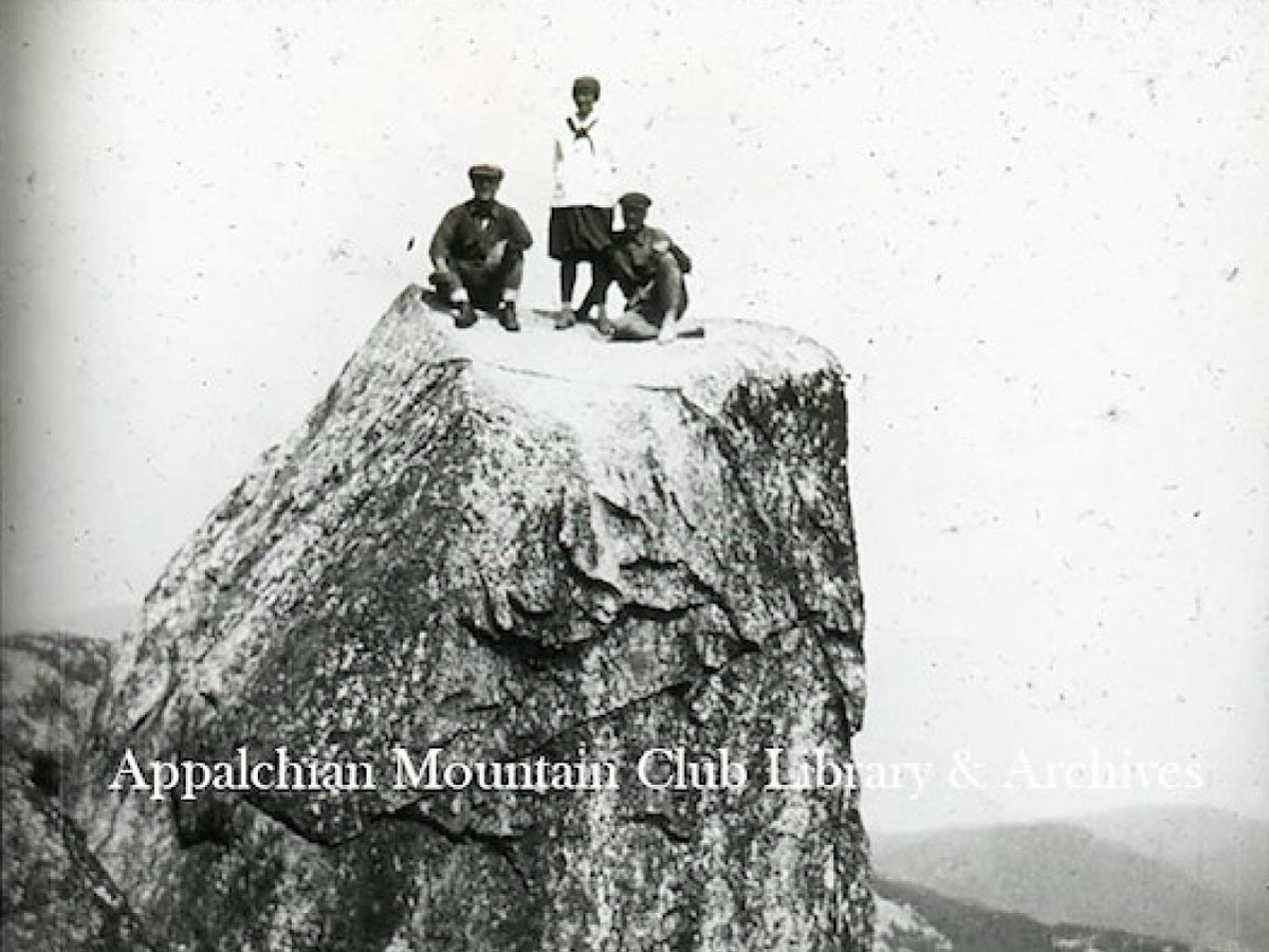 Two men and a woman standing on a boulder