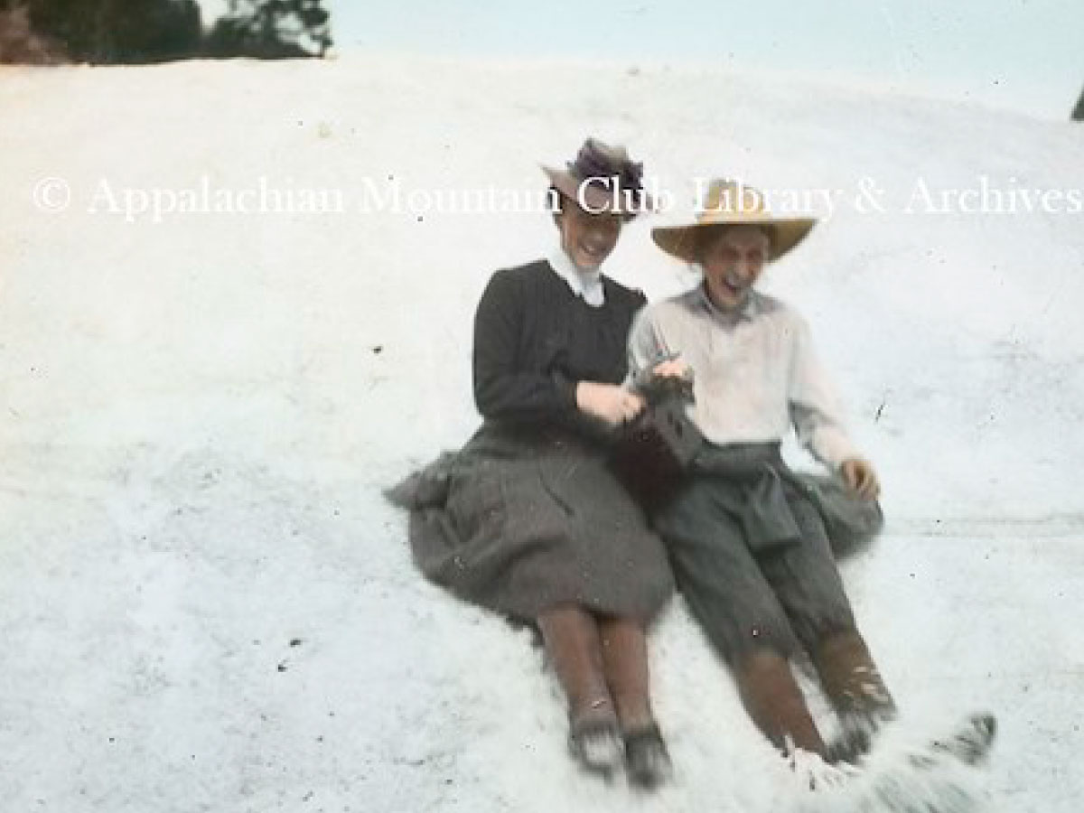 Two women sliding in snow